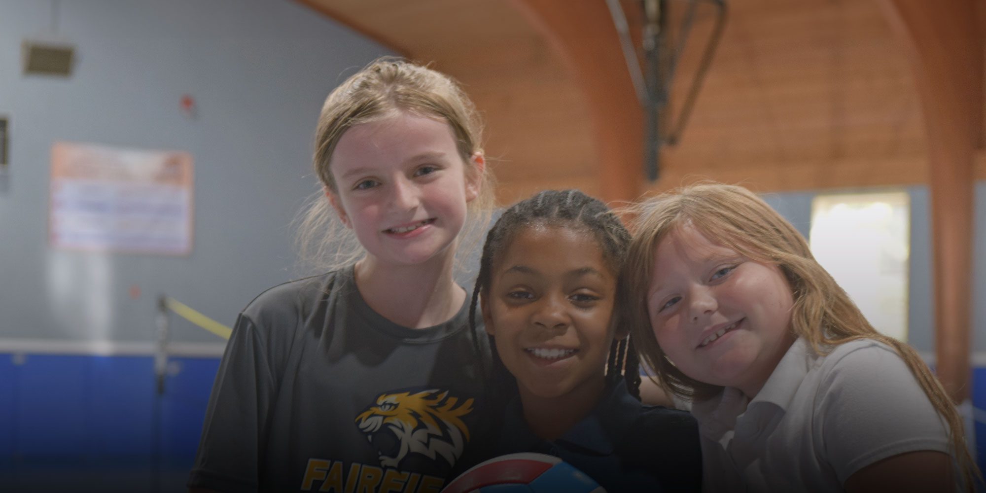 Three smiling Fairfield students posing together indoors.